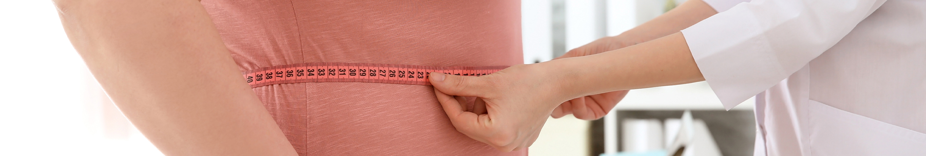 Doctor measuring the abdominal circumference of a male patient.