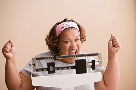 Woman on scale happy with her weight loss results.